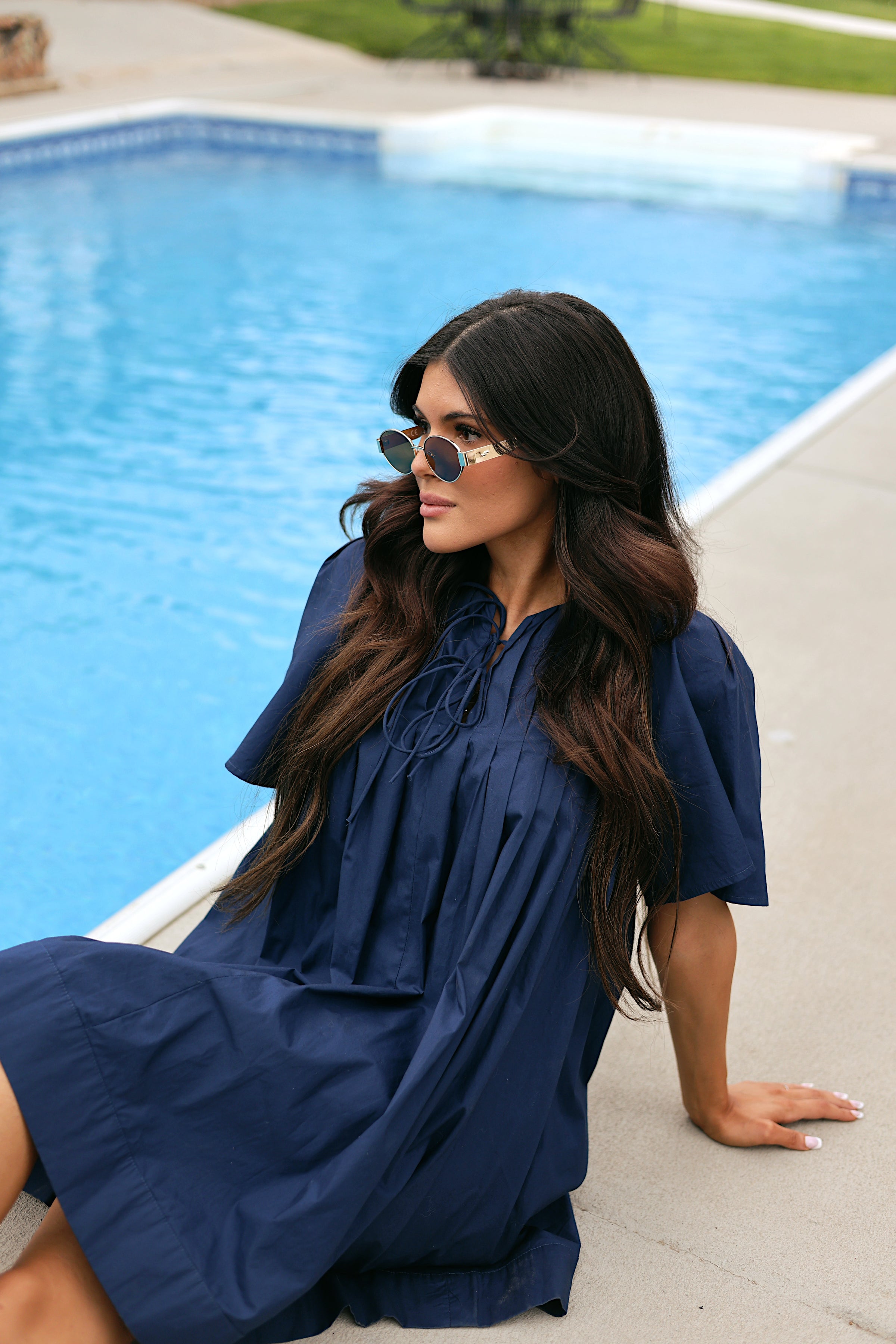 Woman in a blue dress sitting by a pool