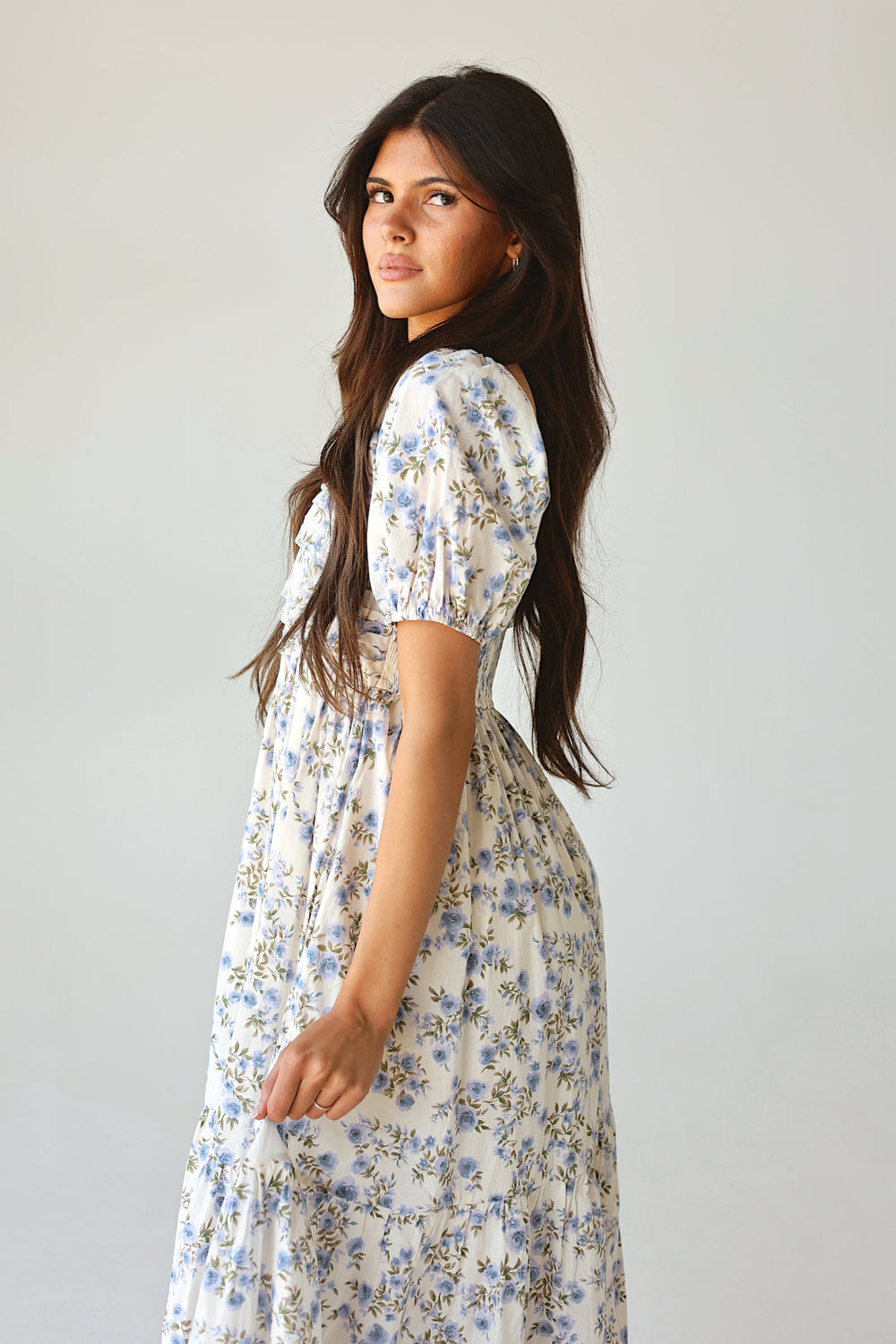 Woman wearing a floral dress against a plain background