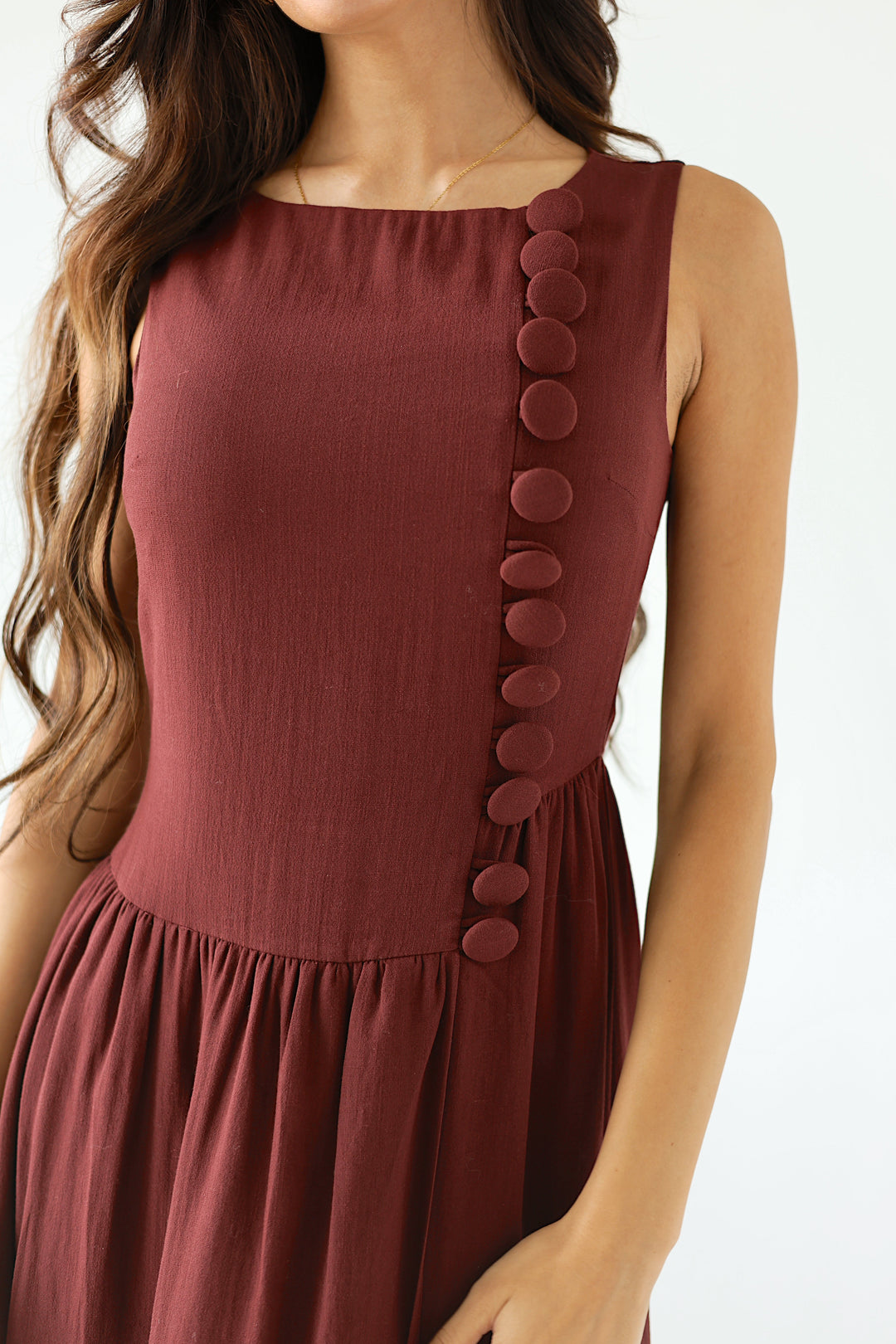 Model in a burgundy sleeveless midi dress with a flowy drop waist silhouette