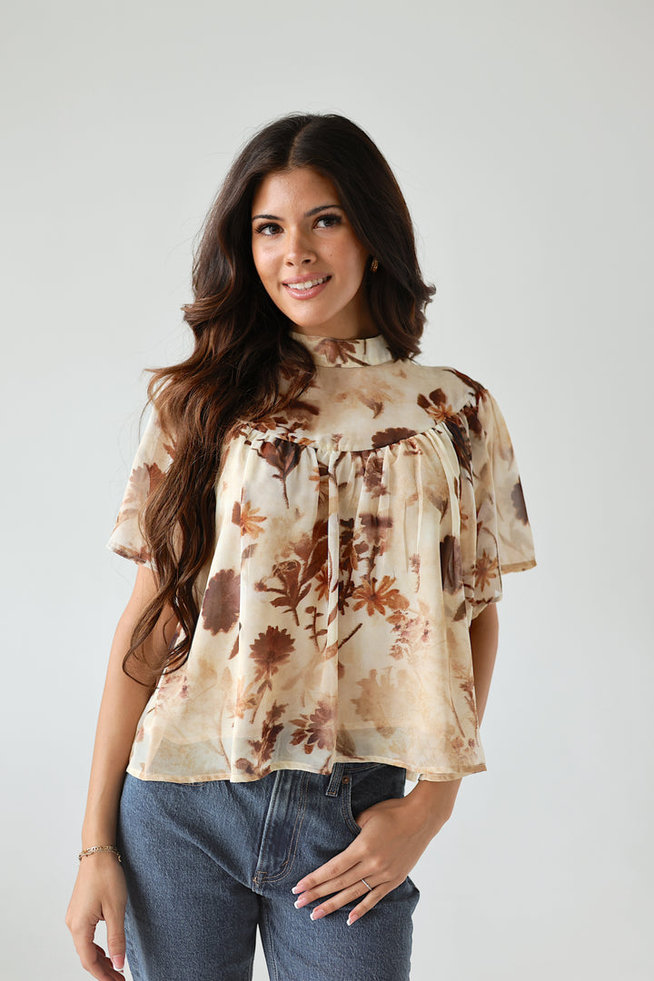 Model wearing the Florence ivory floral mockneck blouse with denim