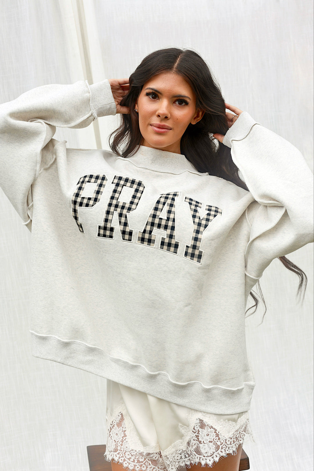 Model wearing the PRAY gingham mockneck sweatshirt in ash grey, front view.