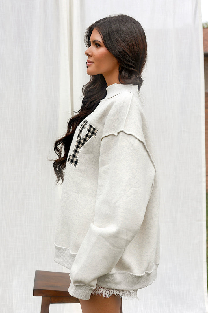 Side view of model wearing the ash grey PRAY mockneck sweatshirt.