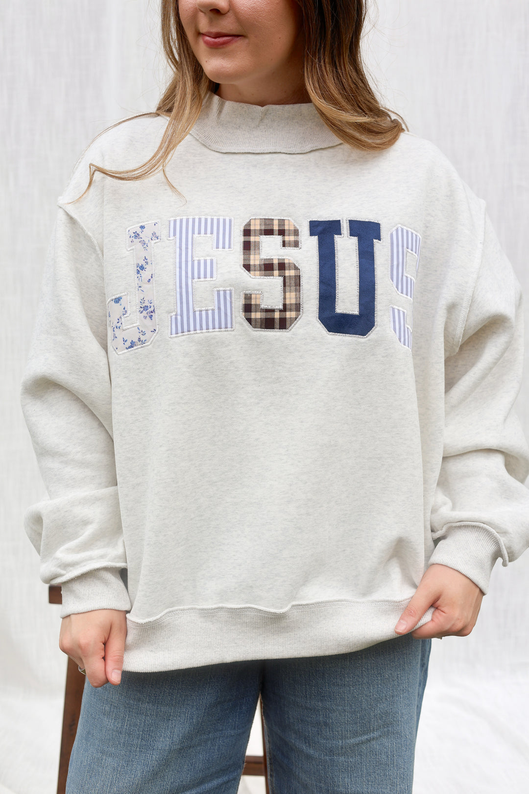 A woman wearing a light heather gray sweatshirt with &