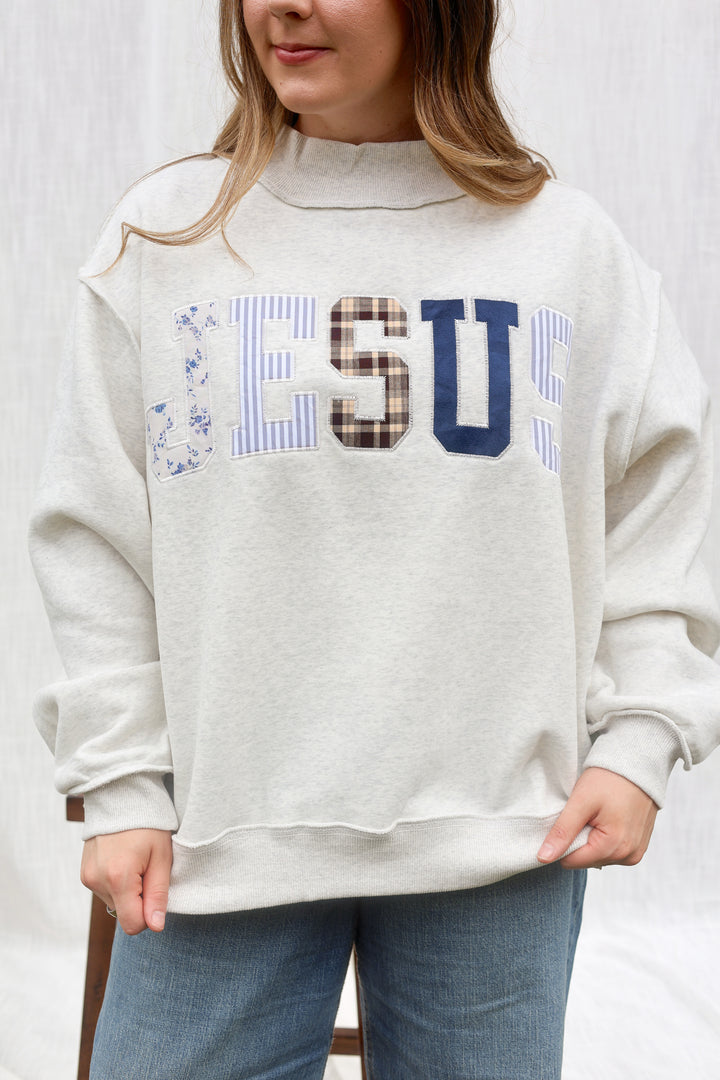 A woman wearing a light heather gray sweatshirt with &