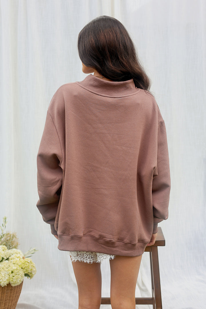 Back view of model wearing the oversized brown JESUS plaid appliqué mockneck sweatshirt.